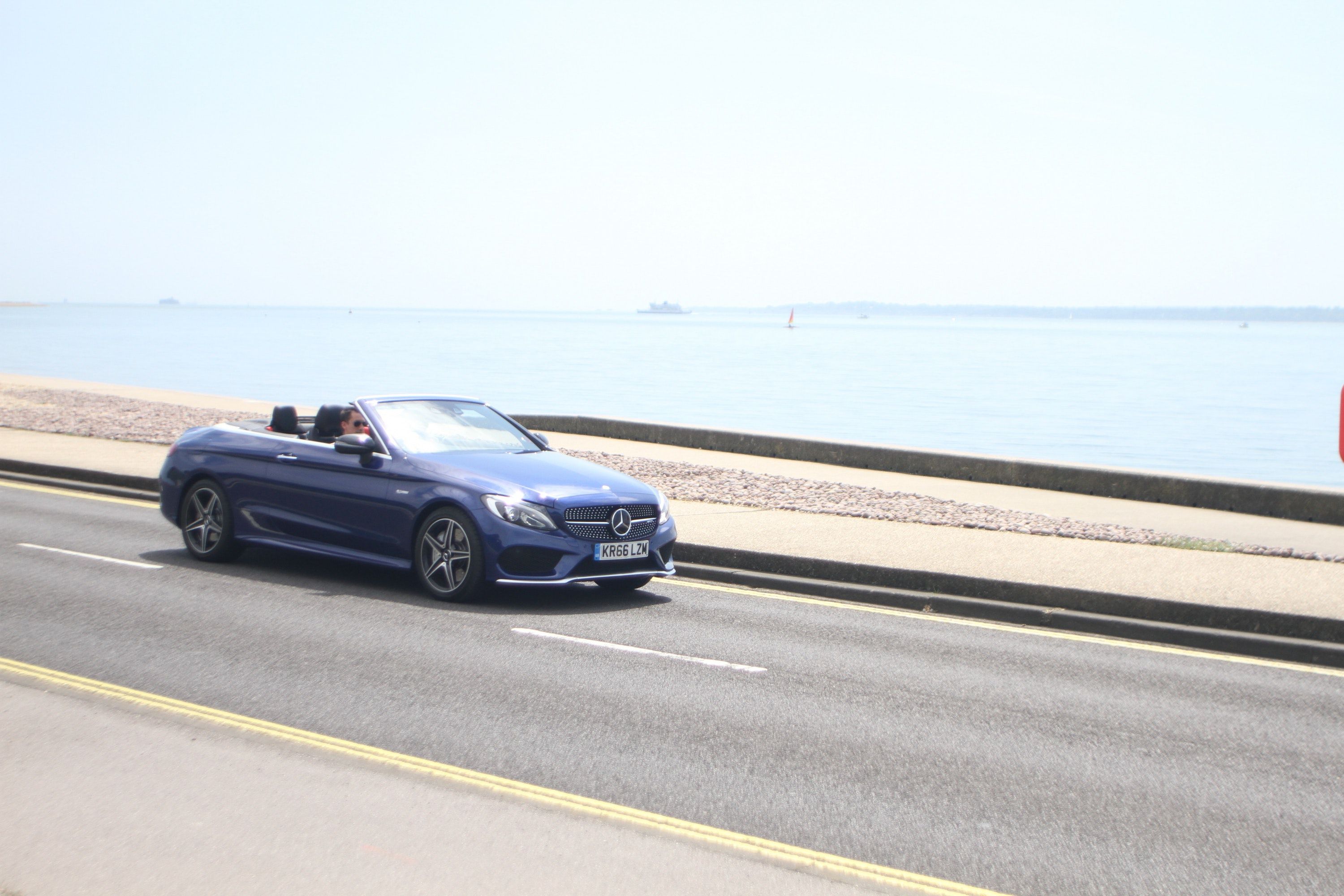 Mercedes Benz convertible car driving slong a seaside road